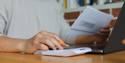 man using calculator while looking at envelope